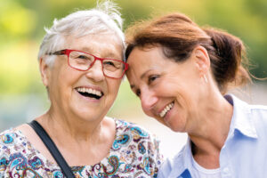 Senior woman with red glasses walking outside with her adult daughter